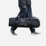 person som bærer pose til sheltair. Bakgrunn er frilagt.