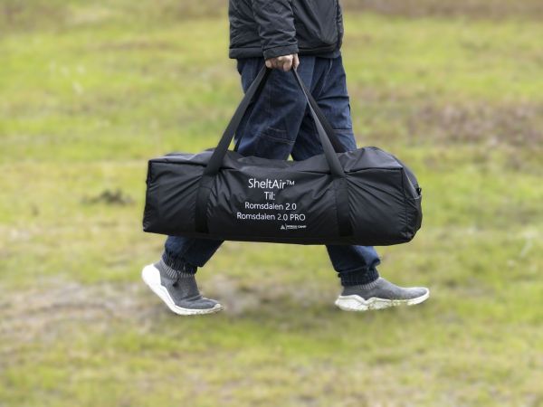 En person som bærer takteltets oppbevaringsveske for enkel transport.