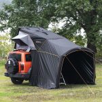 Baksiden av en bil med et taktelt som inkluderer en teltinngang og opphengte paneler for privatliv.