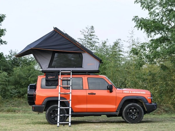 Oransje SUV med Dovre PRO taktelt oppslått – stige montert, grønn skog i bakgrunnen.