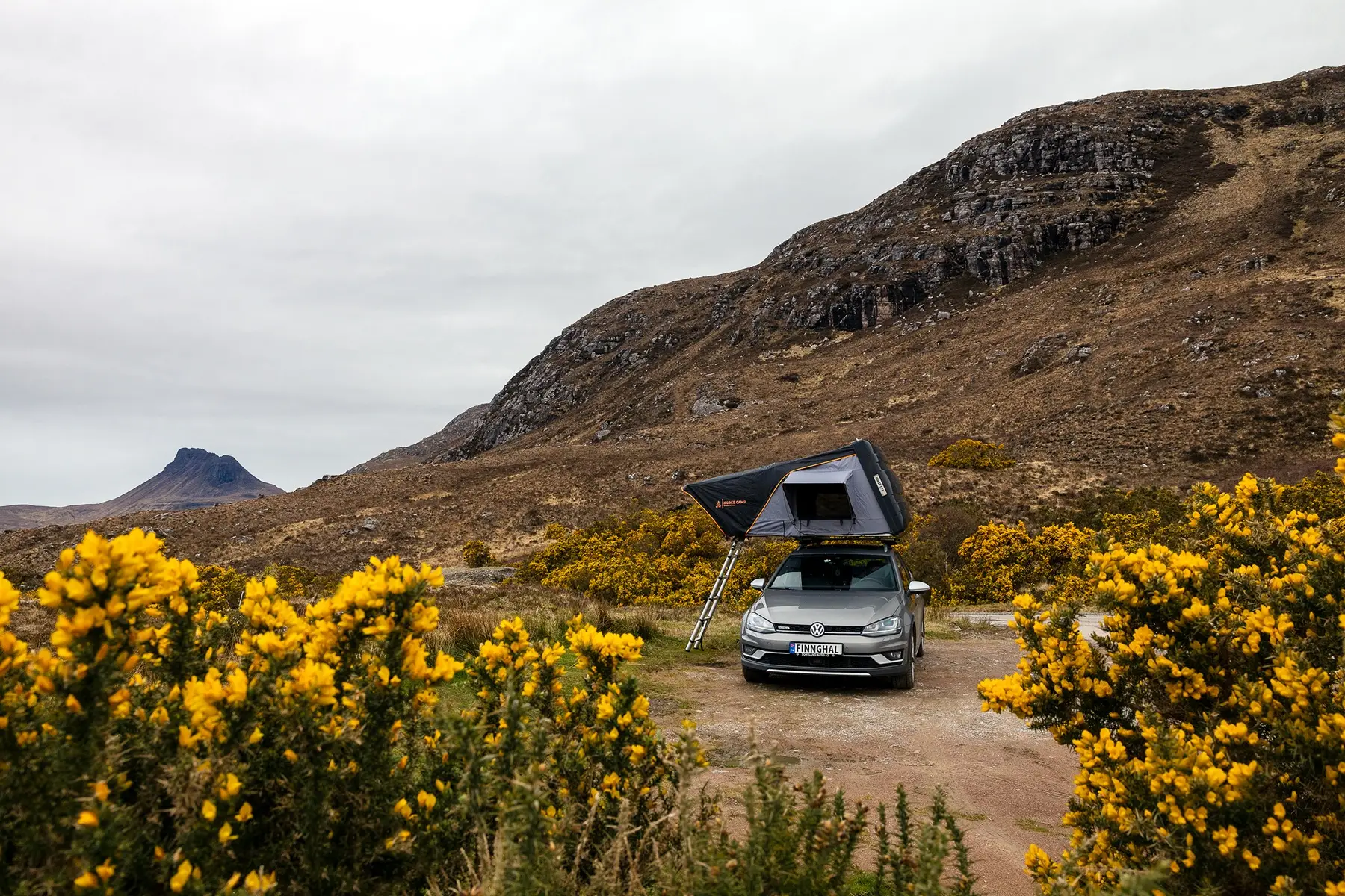 taktelt på grå bil med blomster forgrunn og fjell bak